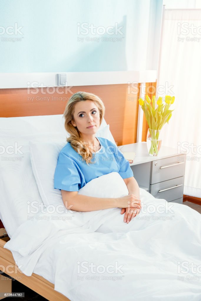 portrait of pensive woman lying in hospital bed